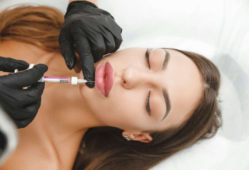 female lips, lip augmentation procedure. A syringe near a woman's mouth, injections to increase